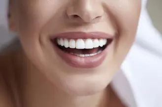 Close‑up of mouth with clean, white, evenly aligned teeth visible in a slight smile, softly blurred background emphasizing dental health.